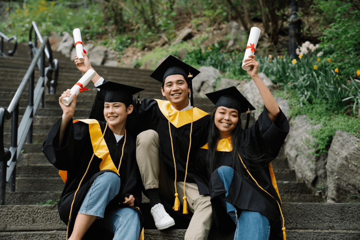 A group of young college graduates, dressed in caps and gowns, joyfully saluting their success, embodying pride and achievement as they celebrate their academic accomplishments.